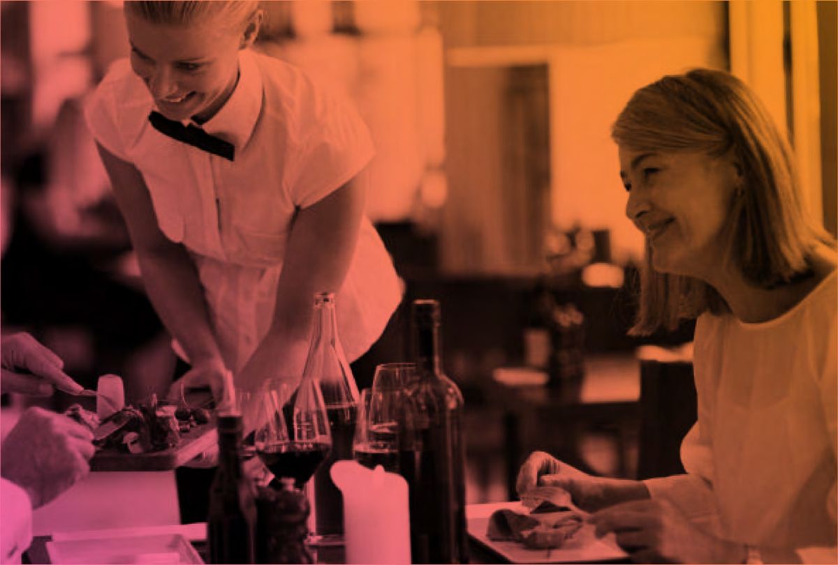 A smiling server attends to a diner at a restaurant table